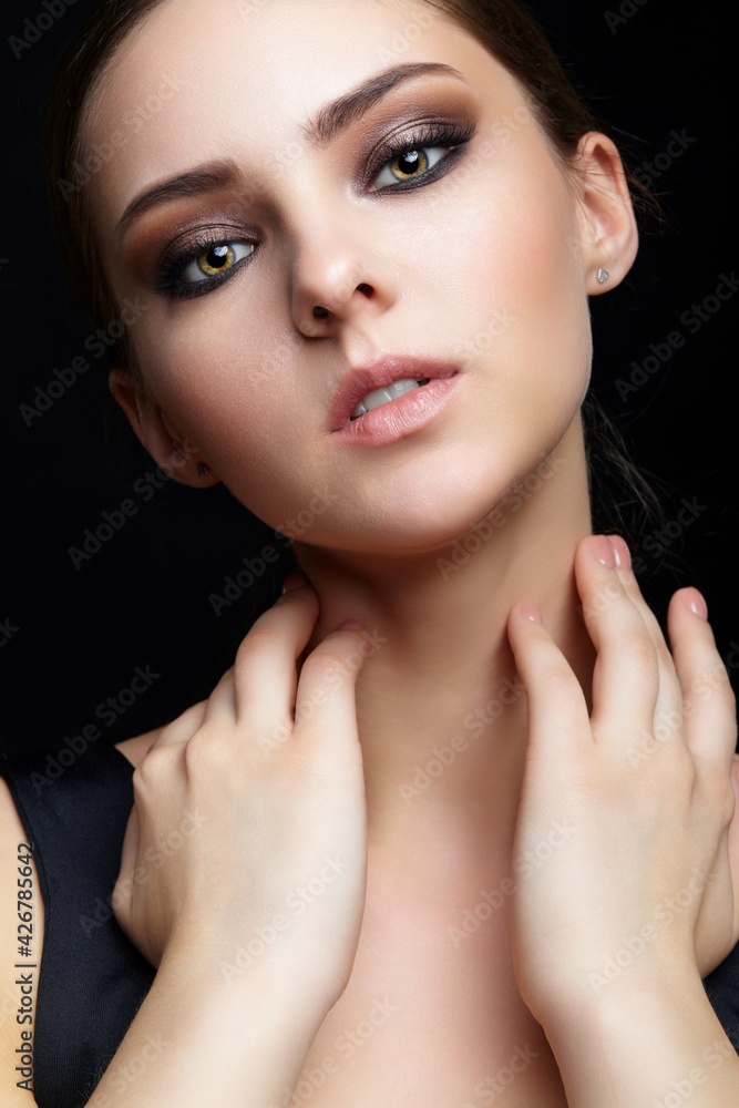 Beauty portrait of young woman with hands on neck on black background. Beauty portrait of young woman with hands on neck on black background.