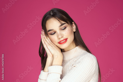 Brunette with long hair red lips cosmetics white sweater pink background cropped view © SHOTPRIME STUDIO