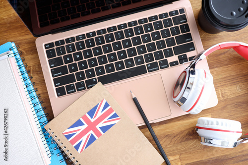 Headphones and english textbooks lying on laptop keyboard closeup photo