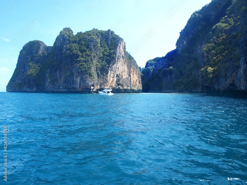 Sea, rocks, turquoise water and luxury white motor yacht anchored near a rocky cliff. Beauty of Thailand nature. Sea voyage, cruise around islands. Tropical resort. Phuket, James Bond Islands, Phi Phi