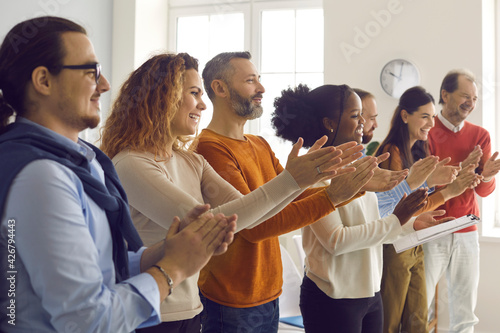 Grateful audience clapping hands showing appreciation to speaker. Group of happy diverse people applauding thanking business trainer or life coach for fun, engaging and enjoyable presentation
