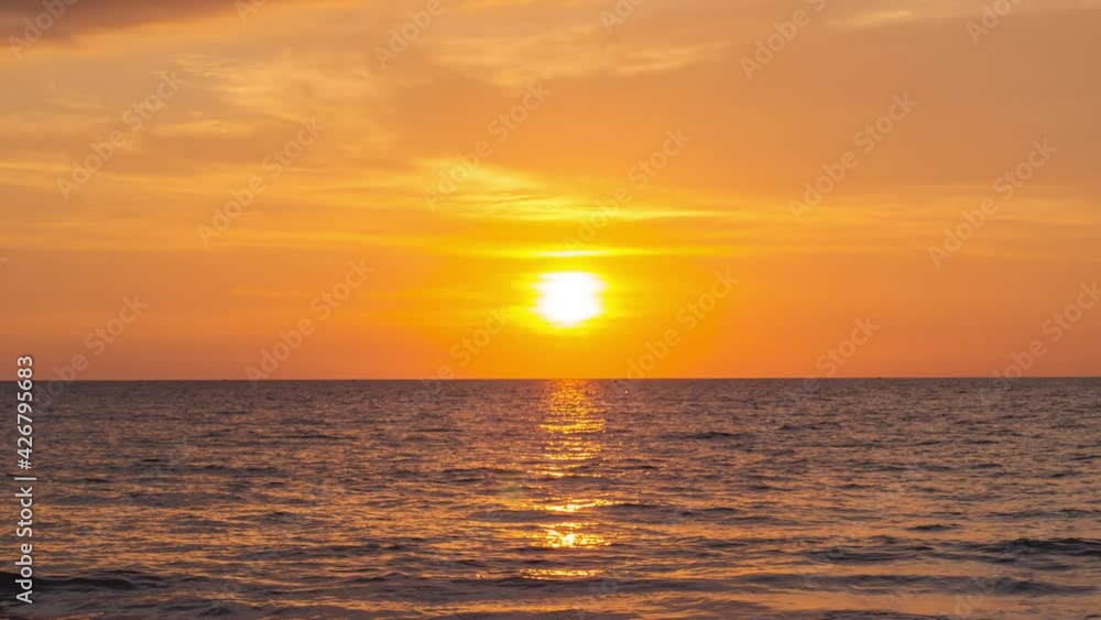 Sunset in golden Sky at sea. Timelapse of the big bright sun moves down. seascape and silhouette of sea waves on the horizon. golden colors of setting sun. Vibrant color nature landscape background Sunset in golden Sky at sea. Timelapse of the big bright sun moves down. seascape and silhouette of sea waves on the horizon. golden colors of setting sun. Vibrant color nature landscape background