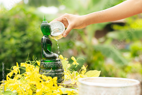 Sprinkle water onto a Buddha Statue in Songkran Festival and Thailand Holiday.
