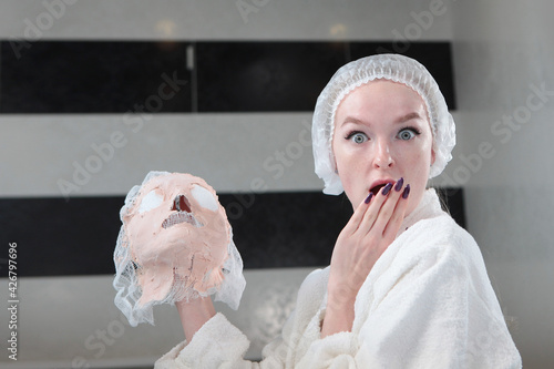 A surprised patient in a beauty salon holds an alginate mask removed from her face. The concept of keeping the skin young and toned.Beauty treatments for the face. Health and facial care. An photo