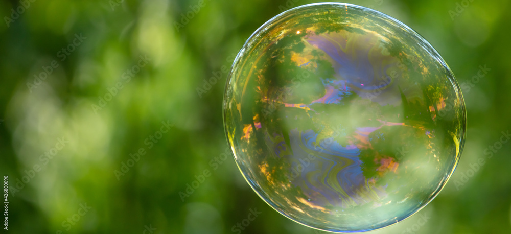A large soap bubble flies in the park. A large soap bubble flies in the park.