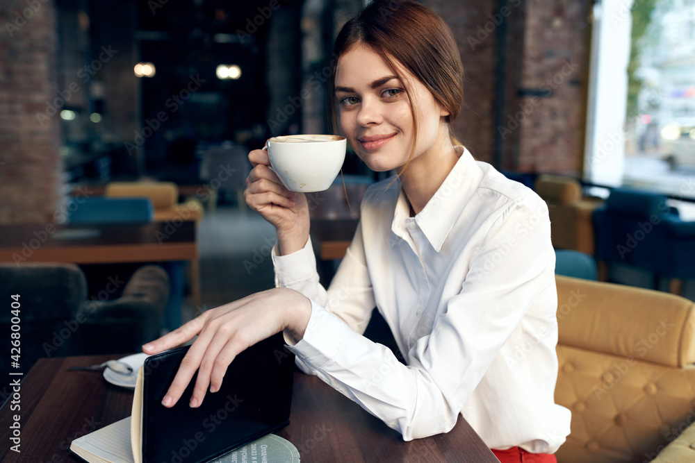 portrait of a beautiful woman with a cup in hand in a restaurant and interior in the background