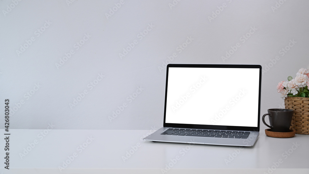 Mock up computer laptop with blank screen, coffee cup and flowers pot on white table. Copy space for products display montage. Mock up computer laptop with blank screen, coffee cup and flowers pot on white table. Copy space for products display montage.