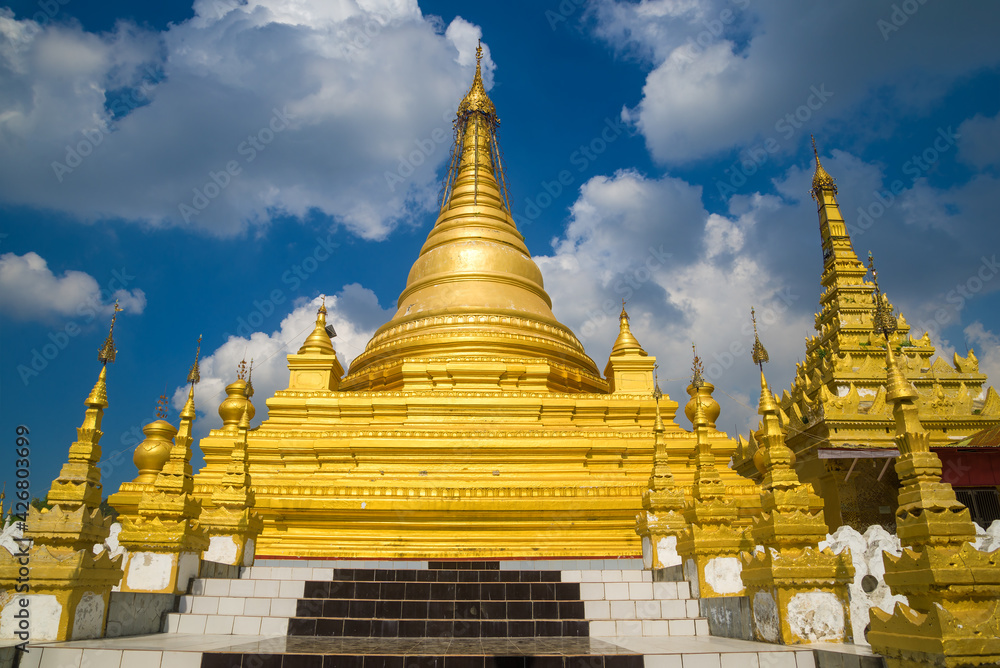 Fototapeta premium One of the golden stupas of the Buddhist temple Kuthodaw Pagoda against the background of the cloudy sky. Mandalay, Myanmar (Burma)