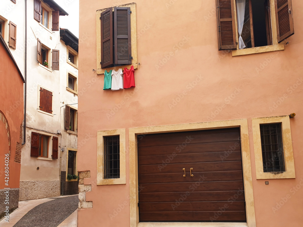 Italian flag in the form of t-shirts that dry on a rope under the window.
