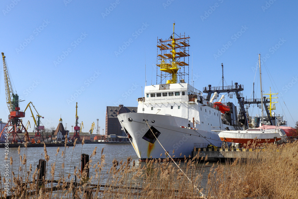 Kaliningrad commercial port. Fishing trawler on the Pregolya river at the pier. There are cranes on the shore