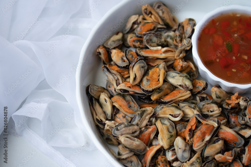 Half a plate of poached mussels with seafood sauce in white plate Half a plate of poached mussels with seafood sauce in white plate