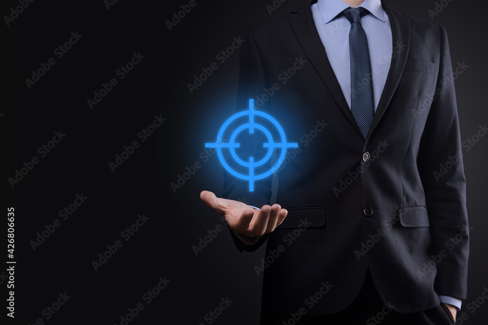 Targeting concept with businessman hand holding target icon dartboard sketch on chalkboard. Objective target and investment goal concept. Targeting concept with businessman hand holding target icon dartboard sketch on chalkboard. Objective target and investment goal concept.