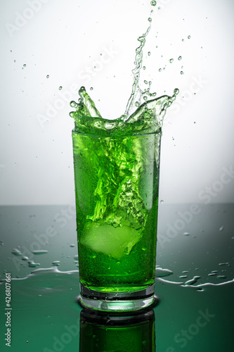 tall transparent glass with green tarragon lemonade on a light background