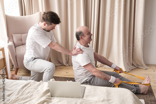 Male yoga trainer helps to senior man to do asana correctly. photo