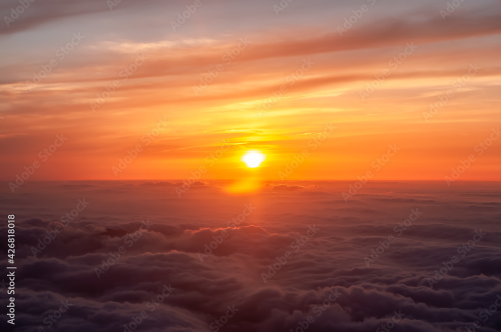 Magnificent scene above the clouds of the orange sunset with beautiful clouds in high relief coloring the sky. Amazing scene seen from an airplane. Feeling of floating.