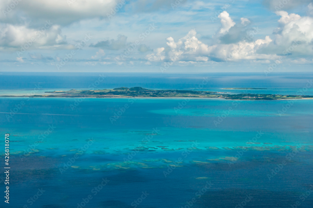 Incredible view of the island of Kohama surrounded by deep turquoise blue, full of corals seen from an airplane.