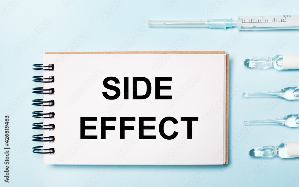 On a blue background ampoule with medicines and a notebook with the text SIDE EFFECT. Medical concept On a blue background ampoule with medicines and a notebook with the text SIDE EFFECT. Medical concept