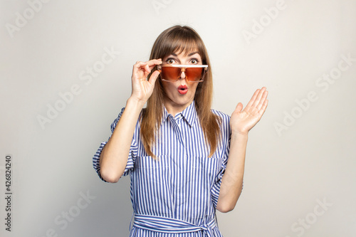 surprised young girl in sunglasses on a light background. Concept summer, vacation, ticket. Banner