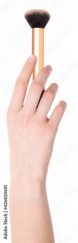 Une main de femme tenant un pinceau à maquillage. A woman's hand holding a makeup brush. Une main de femme tenant un pinceau à maquillage. A woman's hand holding a makeup brush.