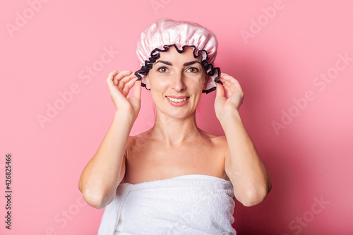 smiling young woman in pink shower cap on pink background.