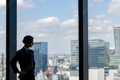 窓から街を眺めるビジネスマン