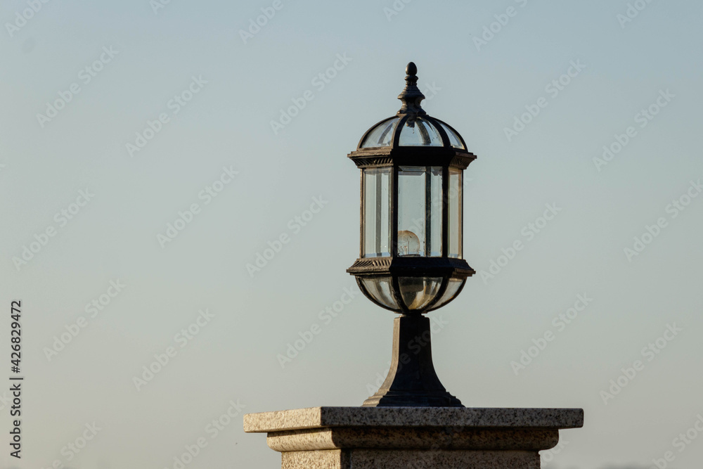 Ornate brass outdoor lantern flood light on top of a marble pillar