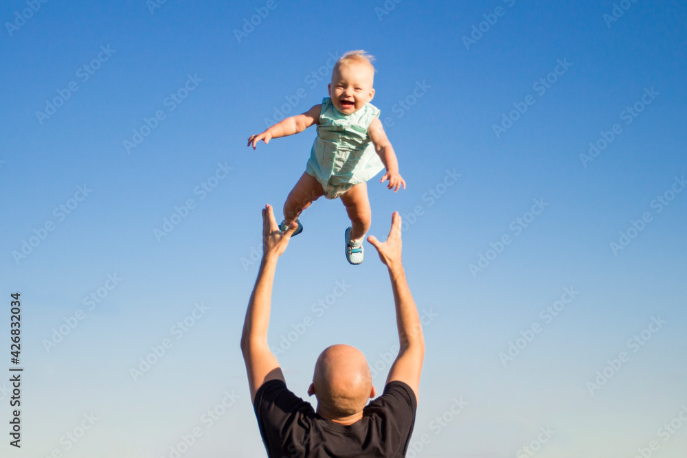 Dad throws his child up against the blue sky. Concept game with children, happy family Dad throws his child up against the blue sky. Concept game with children, happy family