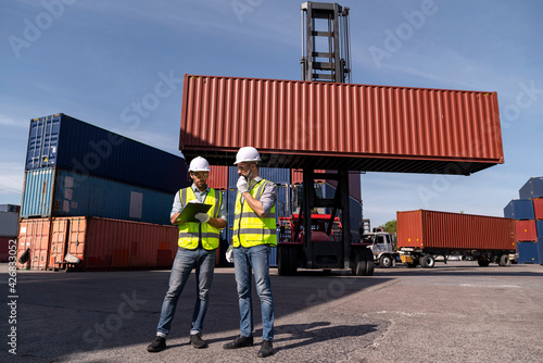 Logistics engineer and inspector working and discuss in shipping container in commercial transport port