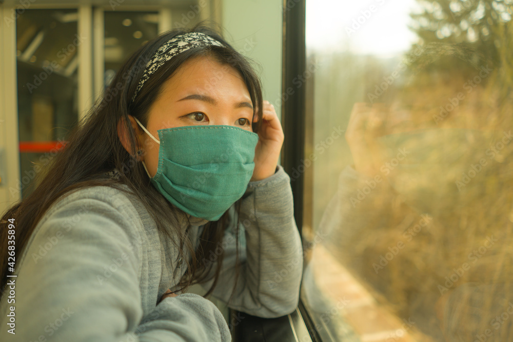 train travel in times of covid19 - young happy and cute Asian Chinese woman in face mask traveling on railcar enjoying landscape through the window train travel in times of covid19 - young happy and cute Asian Chinese woman in face mask traveling on railcar enjoying landscape through the window