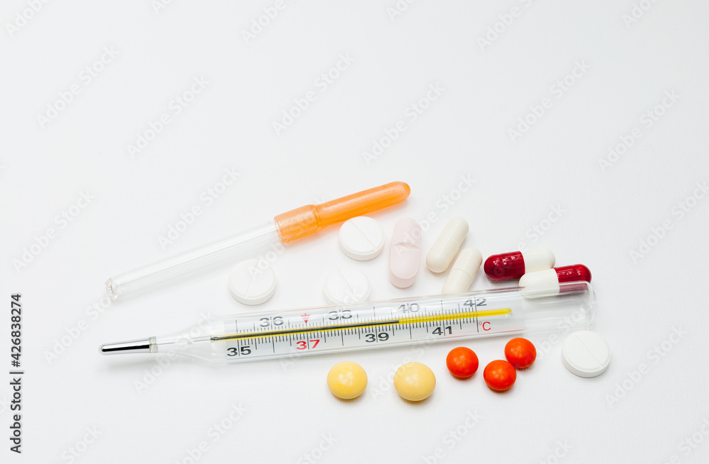 medical mercury thermometer with tablets on a white background medical mercury thermometer with tablets on a white background