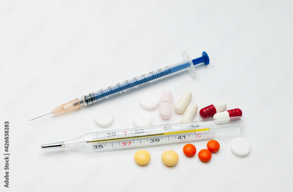 medical mercury thermometer with tablets on a white background medical mercury thermometer with tablets on a white background