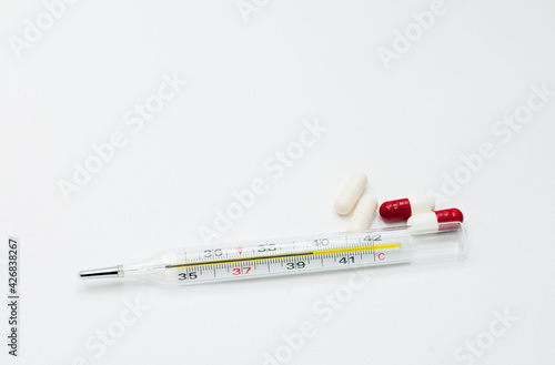 medical mercury thermometer with tablets on a white background