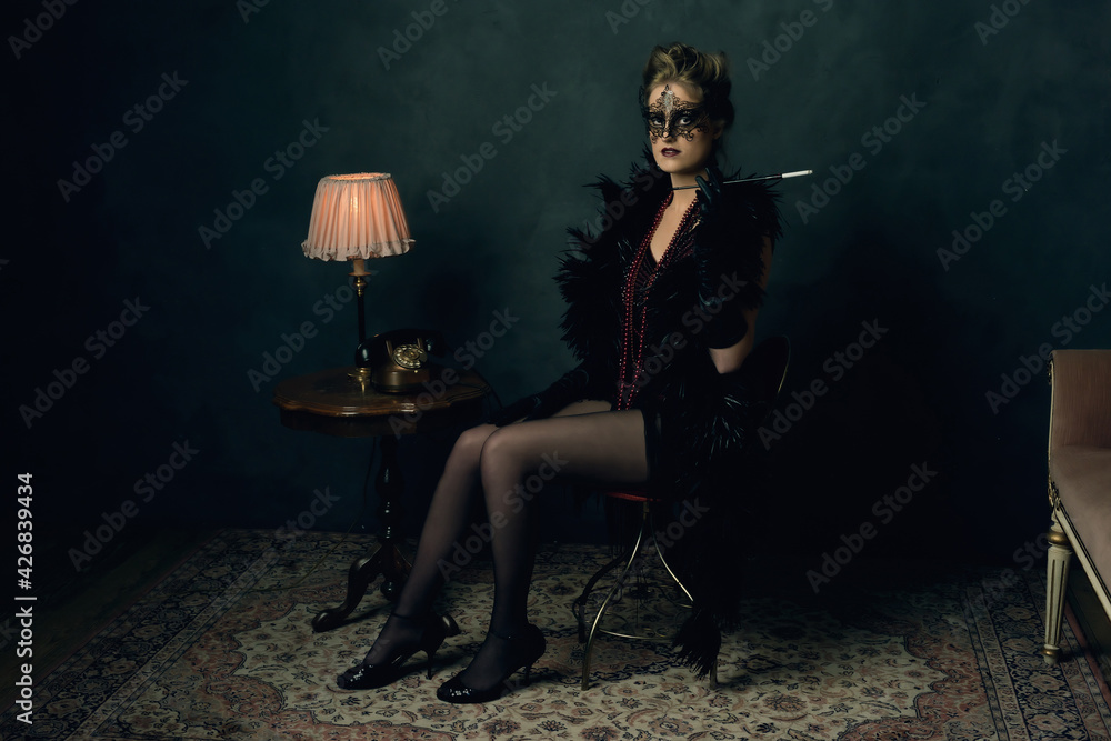 Mysterious young woman with a black boa and mask in retro boudoi Mysterious young woman with a black boa and mask in retro boudoi