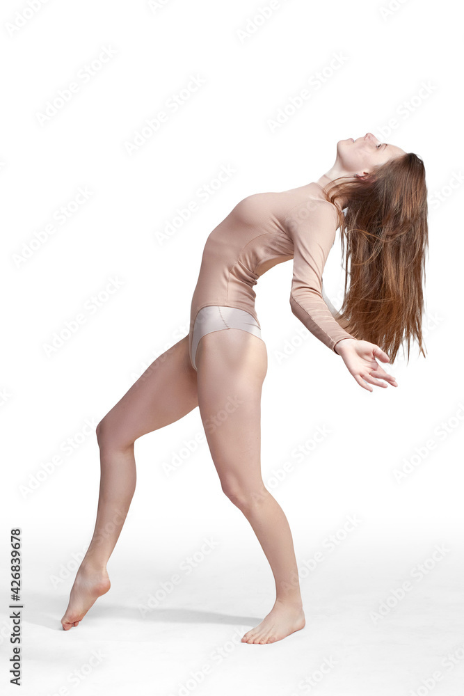 Young slender girl, with long hair, in a beige bodysuit, in the studio on a white background Young slender girl, with long hair, in a beige bodysuit, in the studio on a white background