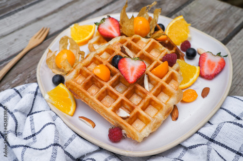 Waffles with blueberries and Strawberry for breakfast on wooden background.