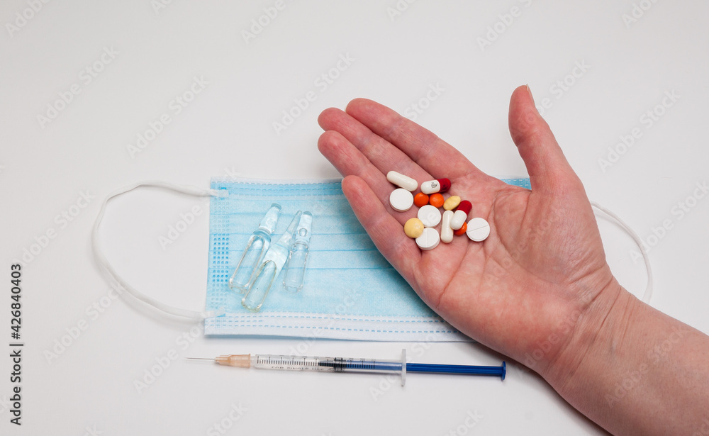 hand with syringe and medical mask and capsules on white background hand with syringe and medical mask and capsules on white background
