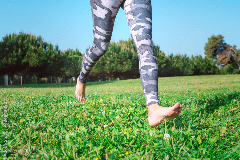 Sporty barefoot woman running on the green grass. Young female legs ...