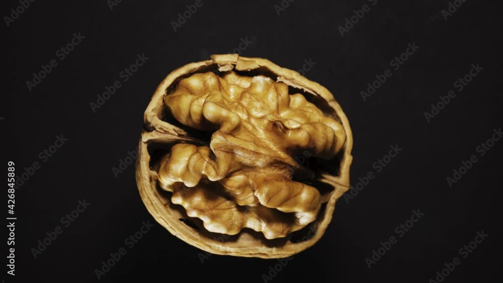 broken in half walnut on a black background rotates. Close-up. View from above. broken in half walnut on a black background rotates. Close-up. View from above.