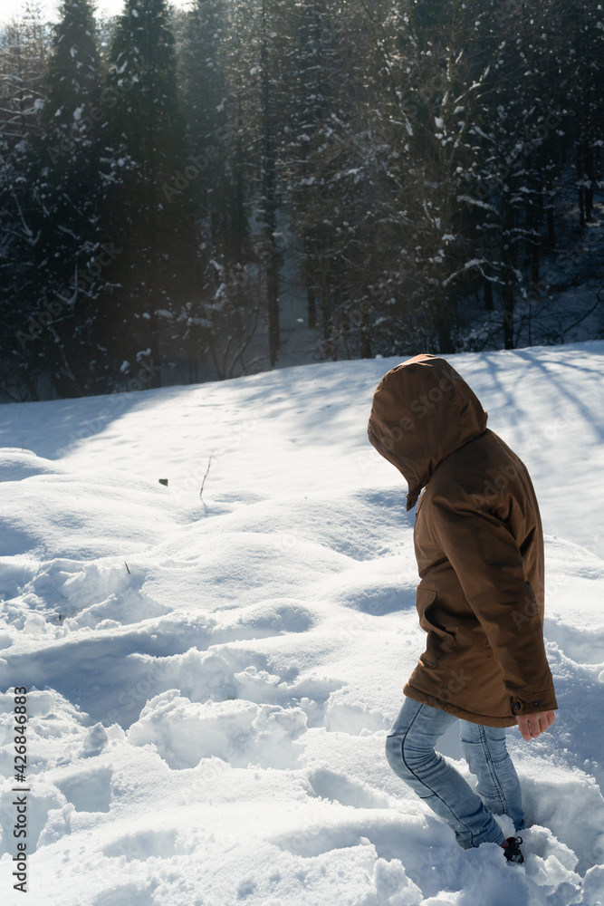 WARM BOY IN FLEECE JACKET AND BROWN HAT WALKS AND PLAYS IN THE SNOW WARM BOY IN FLEECE JACKET AND BROWN HAT WALKS AND PLAYS IN THE SNOW