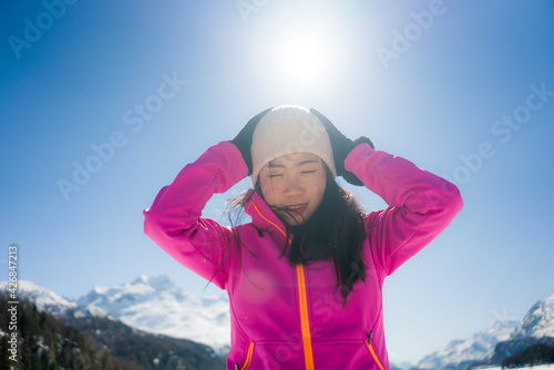 winter holidays at snow mountains - young happy and beautiful Asian woman enjoying cheerful the beauty of frozen lake and snowy landscape at Swiss Alps