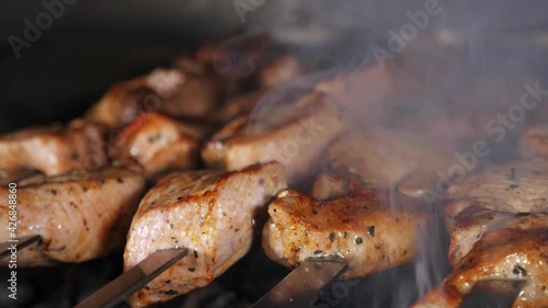 Cooking meat and delicious food concept. Meat on skewers. Marinated shashlik preparing on a barbecue grill over charcoal, close-up in slow motion.