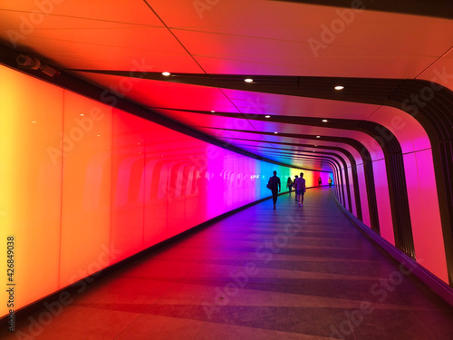 Colourful pedestrian tunnel. You can see shapes of people far away at the other end of the tunnel.