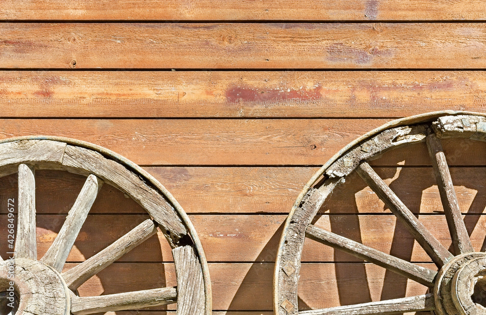  wheels from a cart on a background of a wooden wall