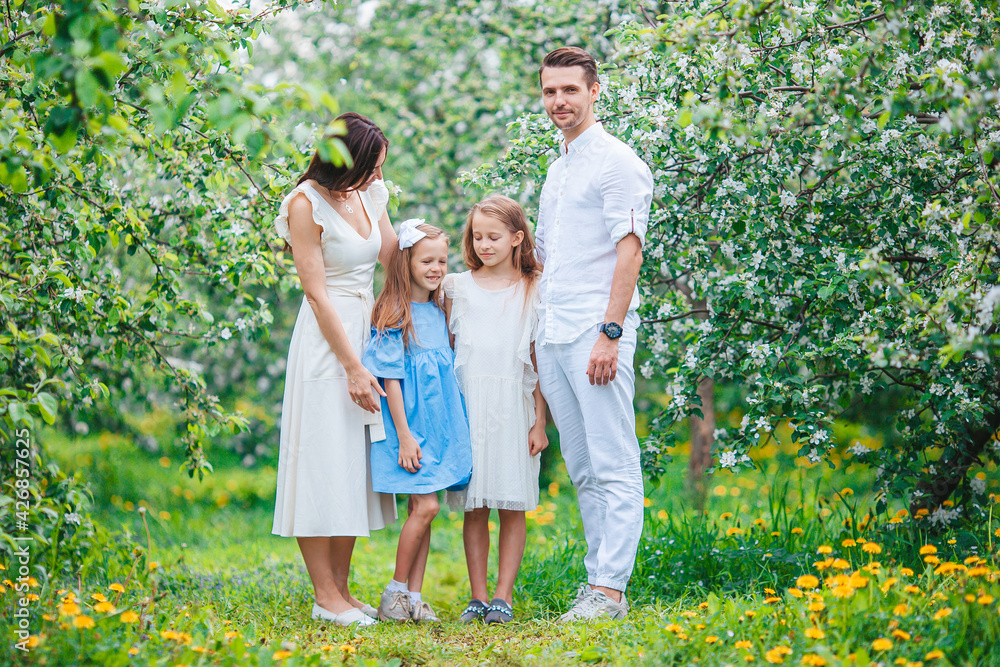 Fototapeta premium Adorable family in blooming cherry garden on beautiful spring day