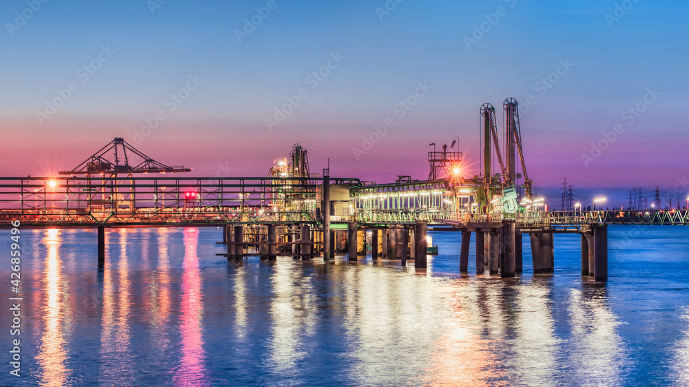 Industrial pier near petrochemical production plant during a colorful sunset, Port of Antwerp, Belgium