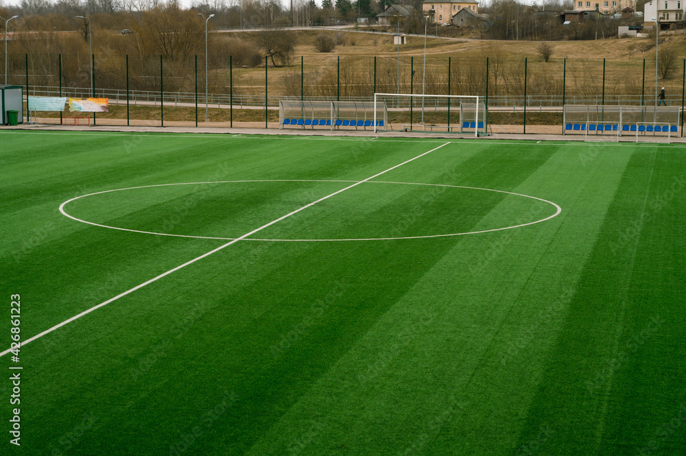Fototapeta premium Open empty football field. Green grass. Cloudy day.