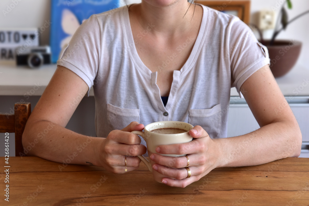 Woman holding cup of coffee with milk and cinnamon powder. Woman holding cup of coffee with milk and cinnamon powder.