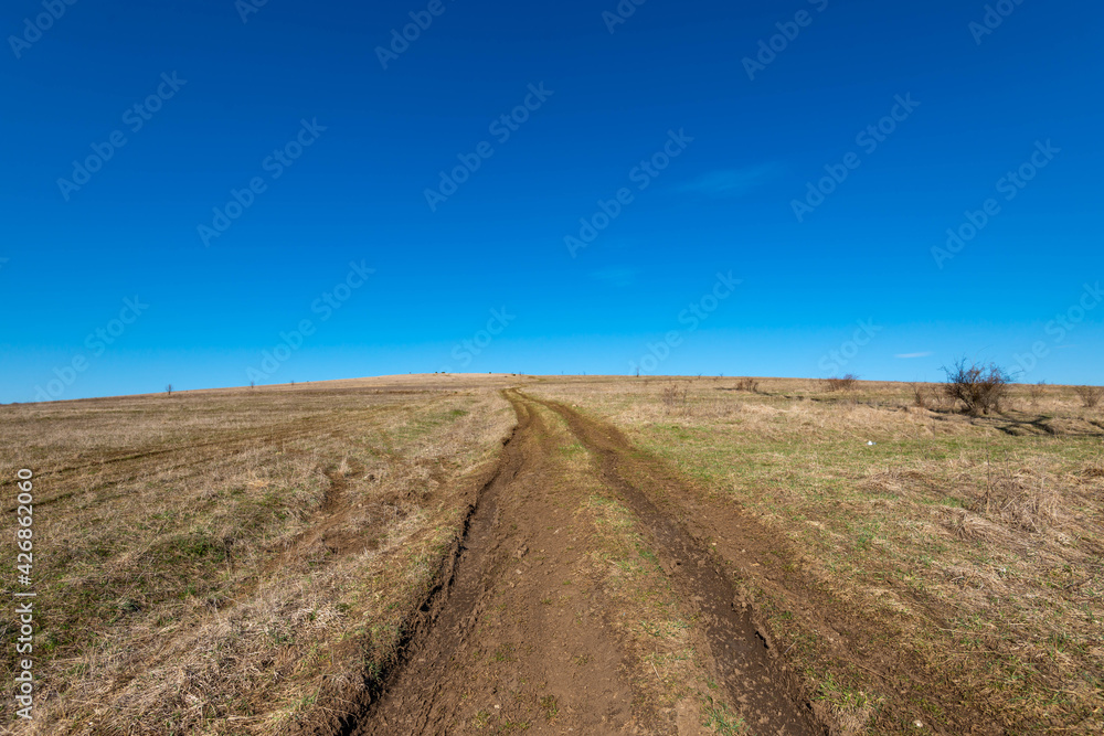 Dirt road leading to the top of the hill, beautiful blue sky in the background at spring.