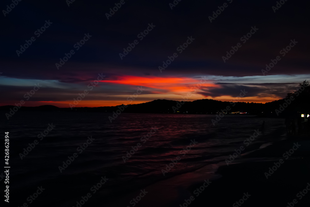 Fototapeta premium Colorful Sea twilight evening sky with cloud, silhouette mountain and wave on the beach, abstract nature