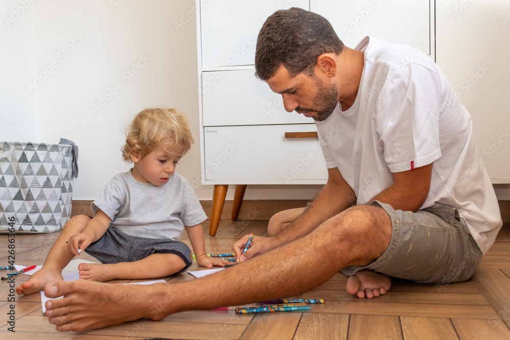 Fototapeta premium PAI E FILHO DESENHANDO JUNTOS NO CHÃO.